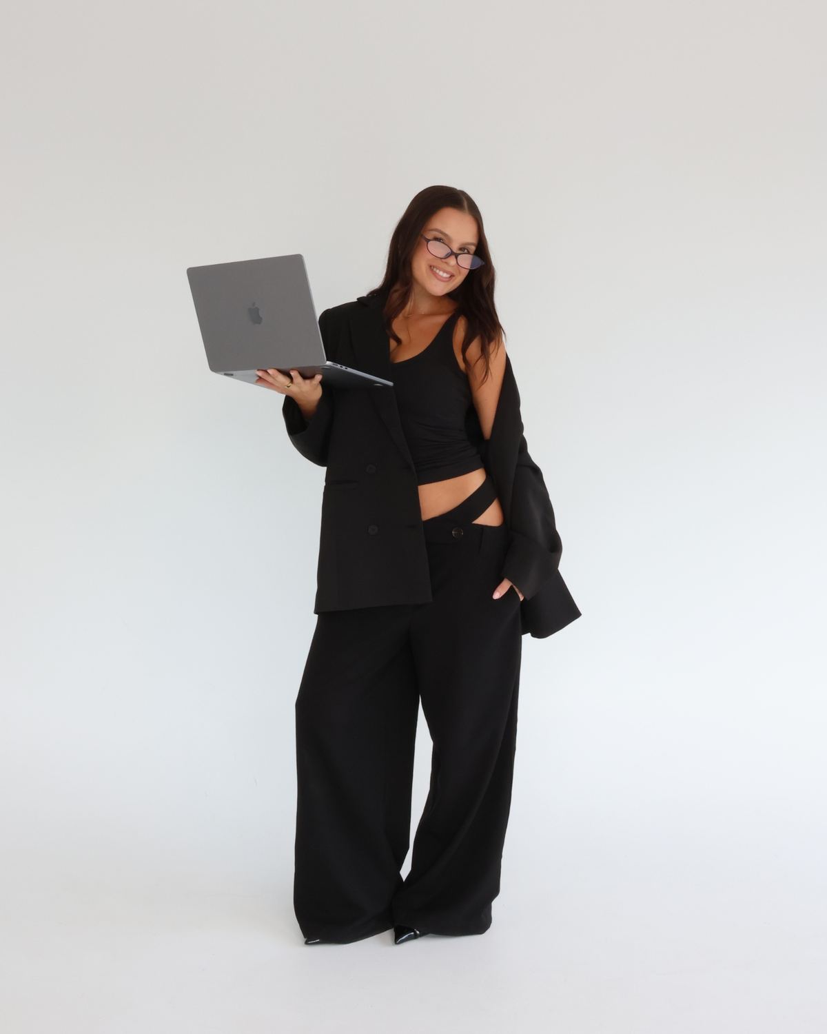 G holding a laptop in a black suit